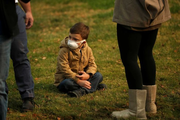 A child in a p2 mask sitting on the grass